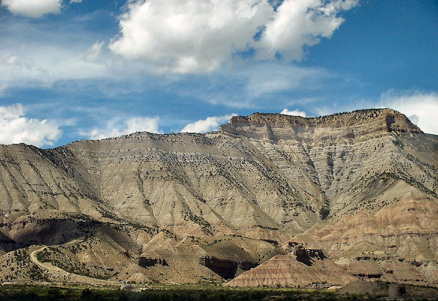 Mesa rising above the community of Battlement Mesa with a blue sky and white clouds on a summer's day.