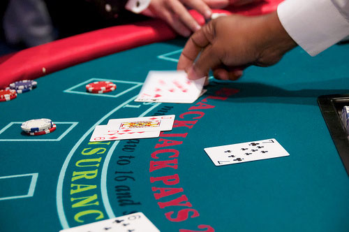A closeup of a black Jack table at a casino in Colorado, shows two players betting with red and white poker chips and playing against the house dealer.