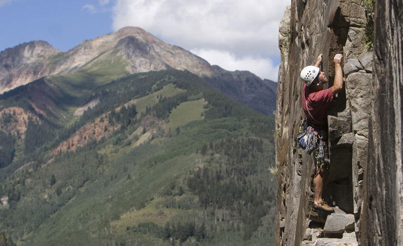 A man in a helmet rock climbing in Colorado's San Juan Mountains