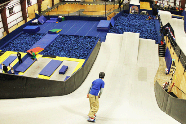 An indoor snowboarder heads down a slope into a pit of blue foam pieces at Woodward at Copper.
