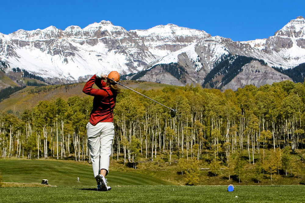 Golfer post swing with mountains in the background